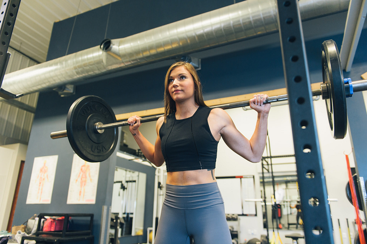 female doing a barbell squat 